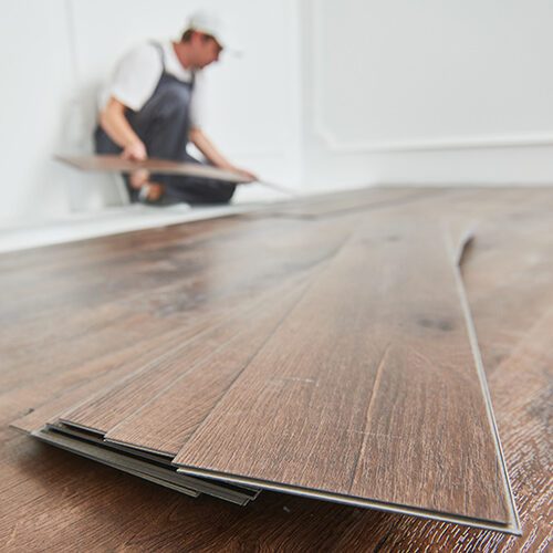 Worker laying down vinyl floor in the home | Howmar Carpet Inc